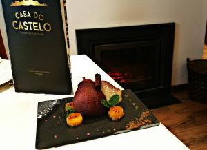 a plate with a pomegranate on a table with a book at Casa do Castelo Ourém in Ourém