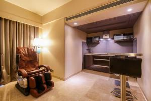a living room with a chair and a kitchen at Sai Palace Grand, Malad in Mumbai
