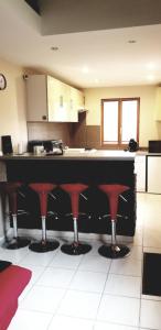 a kitchen with a large counter with red bar stools at Gîte Coeur de Lorraine in Manoncourt sur Seille-Belleau