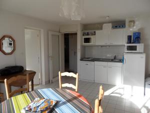 a kitchen with white cabinets and a table and a table and chairs at REF 204 Appartement pour six personnes situé entre port Crouesty et la plage ARZON in Arzon