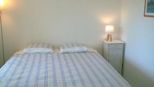 a bed with two pillows and a lamp on a night stand at REF 204 Appartement pour six personnes situé entre port Crouesty et la plage ARZON in Arzon
