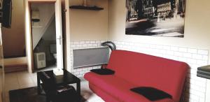 a red couch in a living room with a table at Gîte Coeur de Lorraine in Manoncourt sur Seille-Belleau