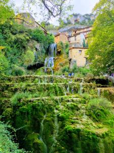 een waterval aan de zijkant van een heuvel met gebouwen bij La Milana, Orbaneja del Castillo in Orbaneja del Castillo