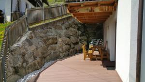 a wooden walkway with two chairs and a stone wall at Casa Simona in Sorafurcia