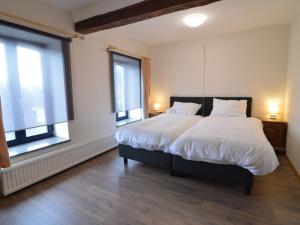una camera da letto con un grande letto bianco con due finestre di Luxurious Holiday Home in Glabbeek with Garden a Bunsbeek