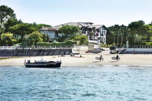 a boat on the beach with people on the beach at Villa du Pyla in Pyla-sur-Mer