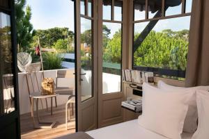 a bedroom with a bed and a balcony with a table at Villa du Pyla in Pyla-sur-Mer