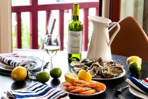 a table with a bottle of wine and a plate of food at Villa du Pyla in Pyla-sur-Mer