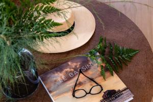 a book on a table with a hat and glasses at Villa du Pyla in Pyla-sur-Mer