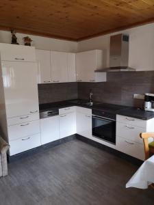 eine Küche mit weißen Schränken und einem schwarzen Herd mit Backofen in der Unterkunft Ferienwohnung Peintnerhof in Innervillgraten