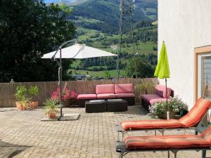 un patio con sofás, una sombrilla, una mesa y sillas en Casa Montana en Niedernsill