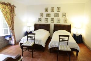 Duas camas num quarto com duas cadeiras e fotografias na parede em Casa da Figueira Velha em Resende mais 19 fotografias