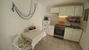 a small kitchen with white cabinets and a table in it at Apartman Goga in Draga Bašćanska