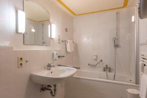 ein weißes Bad mit einem Waschbecken und einer Dusche in der Unterkunft Trip Inn Aschaffenburger Hof in Aschaffenburg
