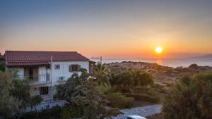 a house with the sunset in the background at Irene Komos in Pitsidia