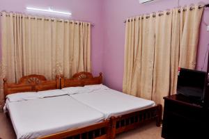 a bedroom with two beds and a tv and curtains at Krishnendu Homestay outer ring road north nada guruvayur in Guruvāyūr