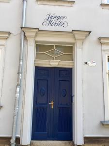 une porte bleue sur un bâtiment blanc avec un panneau au-dessus de celui-ci dans l'établissement Apartment Junger-Moritz, à Erfurt