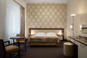 Hotel Malta في كارلوفي فاري: غرفة نوم بسرير وطاولة وكراسي