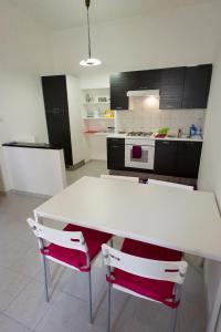 オルヴィエートにあるAppartamento il Gelsominoのキッチン(白いテーブル、赤い椅子2脚付)