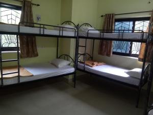 a room with three bunk beds and two windows at Bella Pensao in Parra