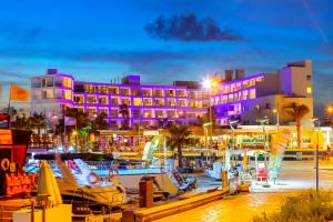 a hotel with purple lights in a marina at night at Limanaki Beach Hotel & Suites in Ayia Napa