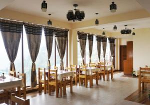 a restaurant with tables and chairs and large windows at Ditto Room Kufri Ashray in Shimla