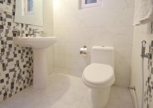 a bathroom with a white toilet and a sink at Ditto Room Kufri Ashray in Shimla
