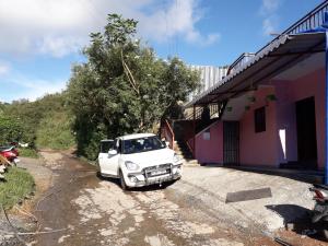 un camion blanc garé sur un chemin de terre à côté d'une maison dans l'établissement Munnar Brindavan Cottage, à Munnar