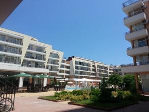 a large apartment building with tables and umbrellas in a courtyard at Menada Grand Kamelia Apartments in Sunny Beach