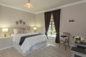 a white bedroom with a bed and a window at Shanzeley Guest House in George