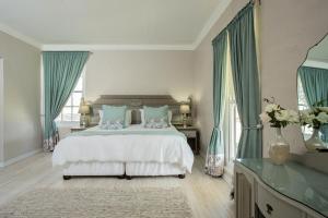 a bedroom with a white bed and green curtains at Shanzeley Guest House in George