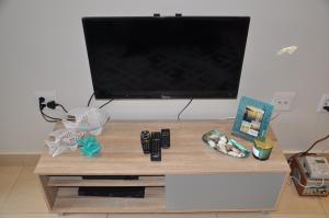 una TV a schermo piatto seduta sopra un centro di intrattenimento in legno di Azure Luxury Apartments Estate a La Mercy