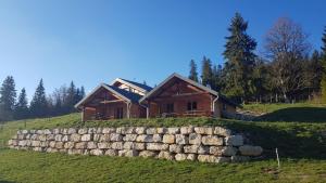 uma casa de madeira numa colina com uma parede de pedra em Chez Liadet em Mouthe