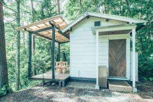 ein winziges Haus mit einer Terrasse im Wald in der Unterkunft Retreat Camp Mahoroba in Fujikawaguchiko
