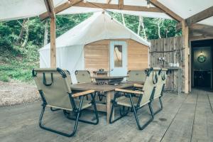 富士河口湖的住宿－Retreat Camp Mahoroba，帐篷,甲板上配有木桌和椅子