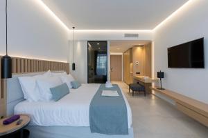 a hotel room with a large white bed and a television at D' Andrea Lagoon All Suites - Adults Only in Marmari