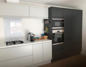 La cuisine est équipée de placards blancs, d'une cuisinière et d'un four micro-ondes. dans l'établissement Fabulous One Bedroom Apartment in Ripon City Centre, à Ripon