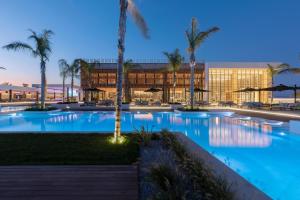 einem großen Pool mit Palmen vor einem Gebäude in der Unterkunft D' Andrea Lagoon All Suites - Adults Only in Marmari