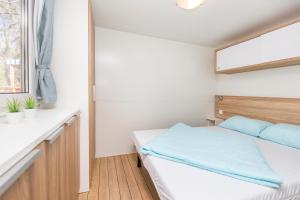 a small bedroom with a bed and a window at Albatross Mobile Homes on Naturist Solaris Camping Resort FKK in Poreč
