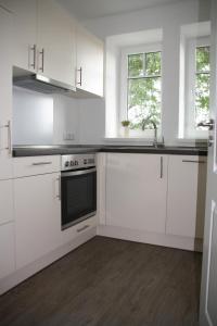 uma cozinha branca com armários brancos e um lavatório em Ferienwohnung Rehblick em Langwedel