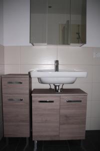 uma casa de banho com um lavatório branco e armários de madeira em Ferienwohnung Rehblick em Langwedel