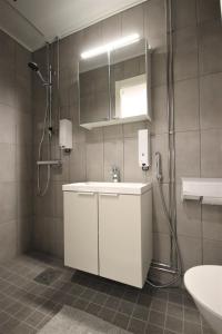 La salle de bains est pourvue d'un lavabo blanc et d'une douche. dans l'établissement Forenom Aparthotel Varkaus, à Varkaus