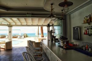 a bar with chairs and a view of the ocean at SunRose Beach Aparthotel in Acharavi