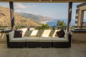 a couch on a balcony with a view of the ocean at Ninfa Apartment - Taormina Holidays in Taormina