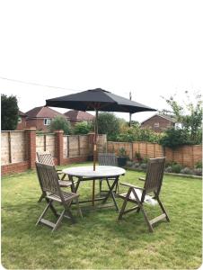 een picknicktafel en twee stoelen met een parasol bij Oak Tree Studio in Marlow