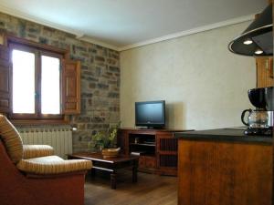 a living room with a tv and a couch and a chair at Apartamentos Pistolo in Ochagavía