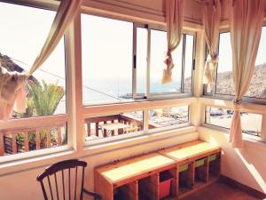 Habitación con ventanas grandes, mesa y banco. en casa honorio, en Playa de Santiago
