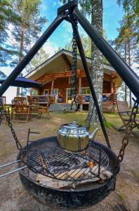 a tea pot on a grill with a log cabin at Vacation Home Kuhmanne in Vehvilä