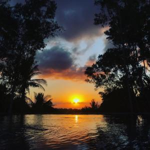 una puesta de sol sobre un cuerpo de agua con árboles en Meket Bungalows, en Nusa Penida