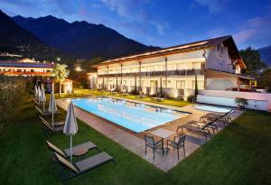 un hotel con piscina y sillas y un edificio en Appartement-Hotel Anthea, en Tirolo